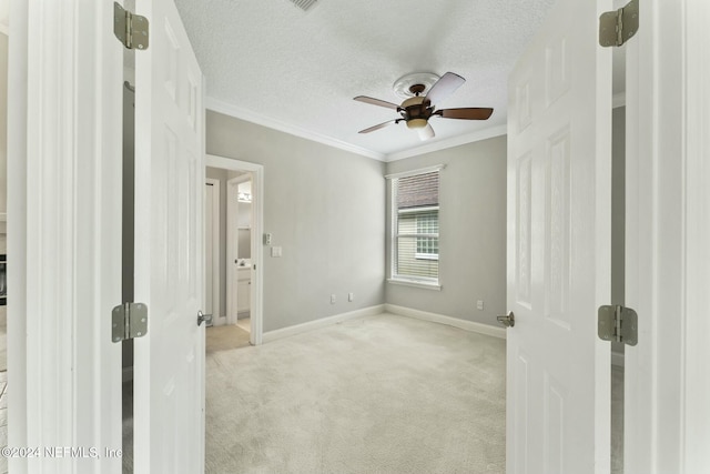 carpeted empty room featuring ceiling fan, ornamental molding, and a textured ceiling