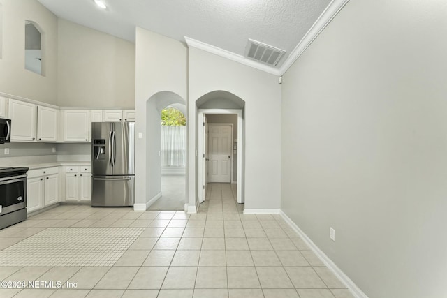 kitchen featuring high vaulted ceiling, white cabinets, light tile patterned floors, a textured ceiling, and stainless steel appliances