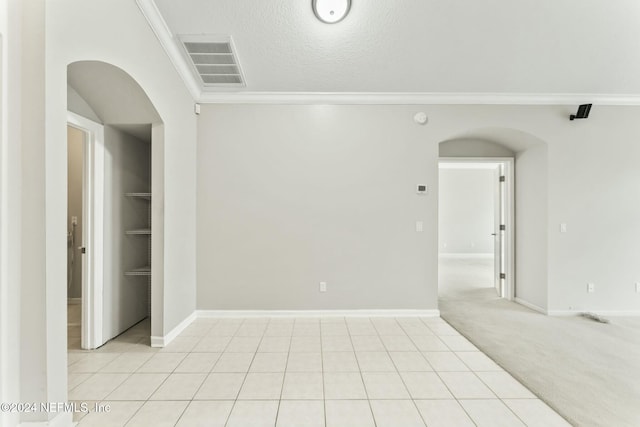 carpeted empty room with built in shelves, crown molding, and a textured ceiling