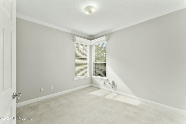 spare room with a textured ceiling, crown molding, and light carpet