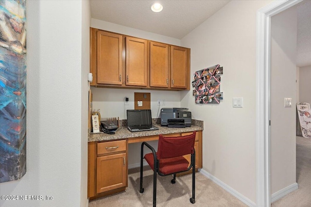 home office with light carpet, built in study area, and baseboards