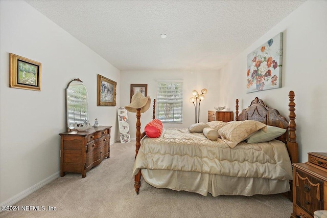 bedroom with light colored carpet, a textured ceiling, and baseboards