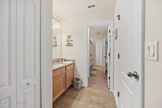 bathroom featuring visible vents, tile patterned floors, a textured ceiling, vanity, and a closet