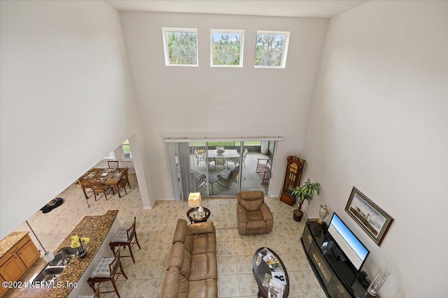 living area with light tile patterned floors and a high ceiling