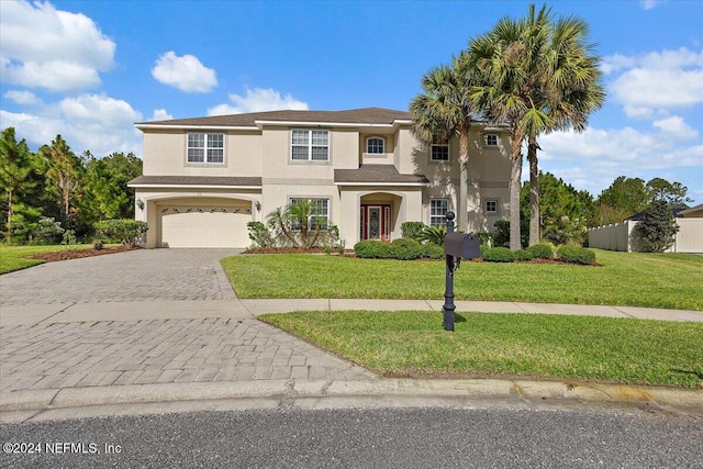 view of front of house featuring a garage, decorative driveway, a front lawn, and stucco siding