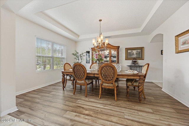 20 Sadie Ct, Saint Augustine, FL 32095 - dining area with a tray ceiling, arched walkways, a chandelier, light wood-style flooring, and baseboards