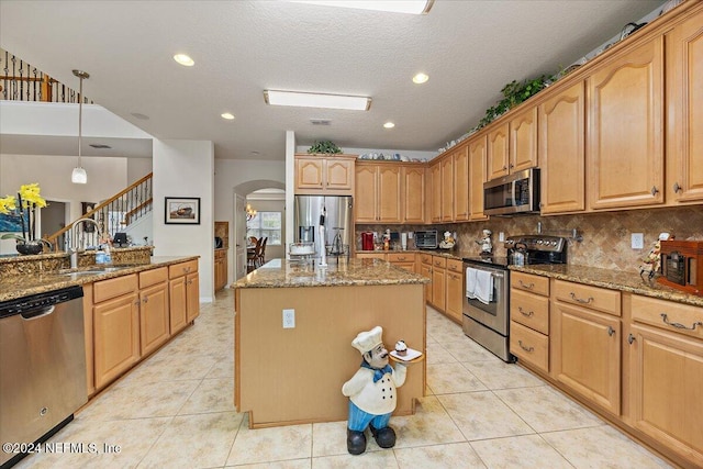 kitchen featuring light stone counters, decorative light fixtures, stainless steel appliances, light tile patterned flooring, and a kitchen island