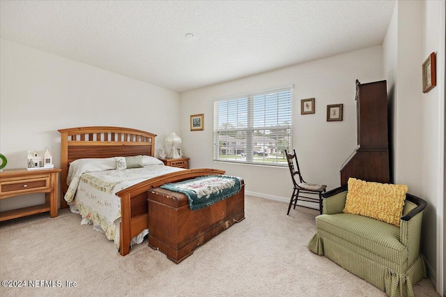 bedroom with light carpet, a textured ceiling, and baseboards