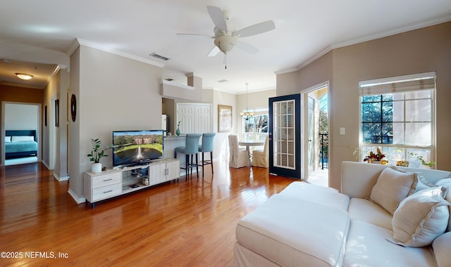 living room with hardwood / wood-style floors, crown molding, plenty of natural light, and ceiling fan with notable chandelier