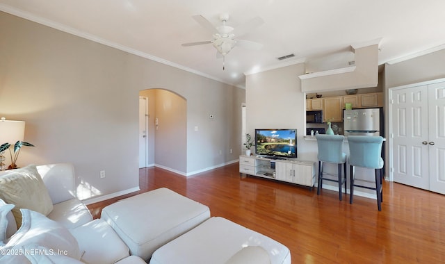 living room featuring ceiling fan, ornamental molding, and dark hardwood / wood-style floors