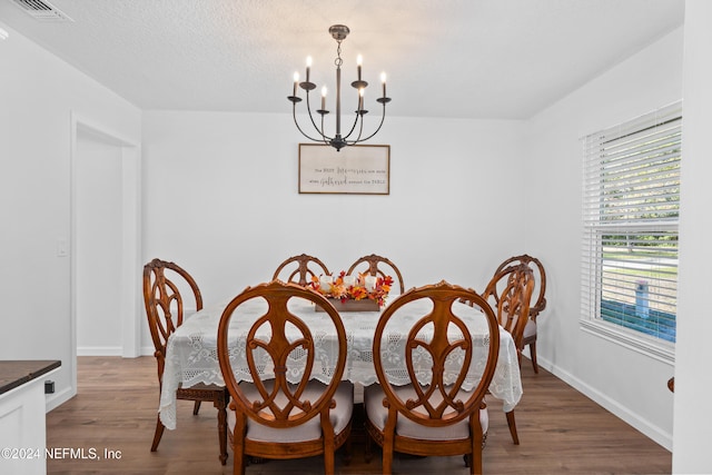 dining space featuring a notable chandelier, dark hardwood / wood-style flooring, and a textured ceiling