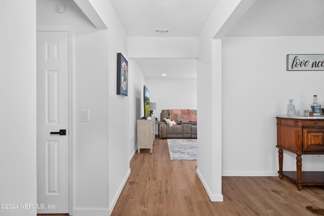 hallway featuring a textured ceiling and light wood-type flooring