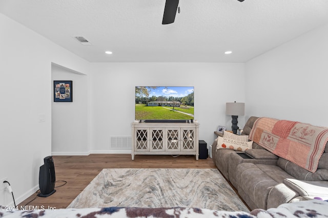 living room with ceiling fan, wood-type flooring, and a textured ceiling