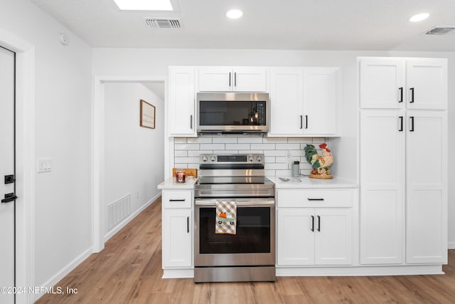 kitchen featuring decorative backsplash, light hardwood / wood-style floors, white cabinetry, and appliances with stainless steel finishes