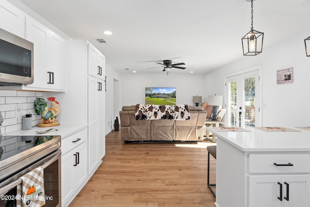 kitchen with stainless steel appliances, ceiling fan, pendant lighting, light hardwood / wood-style flooring, and white cabinetry