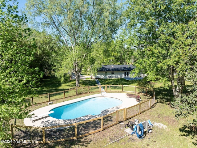 view of swimming pool featuring a yard and a diving board