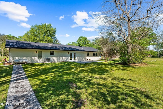 rear view of house featuring a yard, central AC unit, and french doors