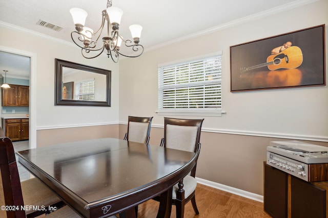 dining area featuring crown molding, a chandelier, and light hardwood / wood-style floors