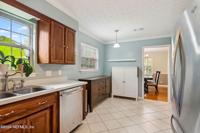 kitchen featuring crown molding, sink, hanging light fixtures, a textured ceiling, and appliances with stainless steel finishes