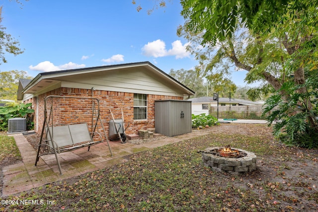 back of property featuring central air condition unit and an outdoor fire pit