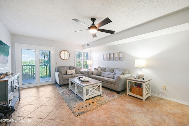 living room with a textured ceiling, ceiling fan, and light tile patterned flooring