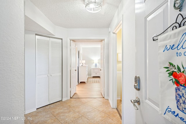 hallway featuring light tile patterned floors and a textured ceiling