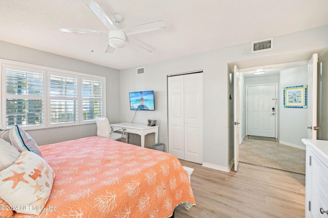 bedroom featuring ceiling fan, a closet, light hardwood / wood-style floors, and a textured ceiling