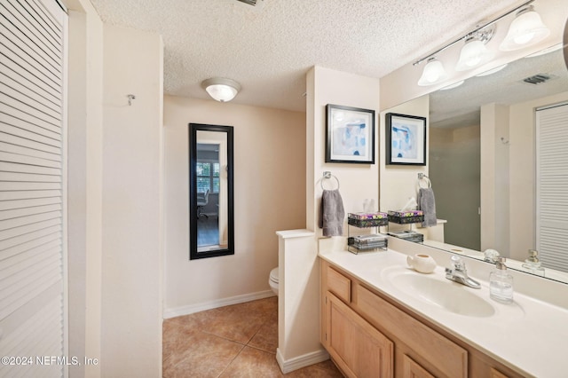 bathroom with toilet, a textured ceiling, vanity, and tile patterned floors