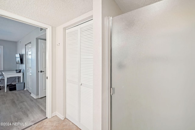 corridor with a textured ceiling and light hardwood / wood-style floors