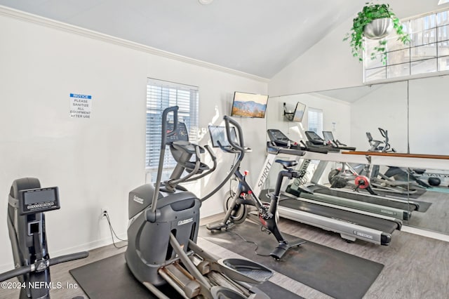 exercise room with wood-type flooring, ornamental molding, and vaulted ceiling