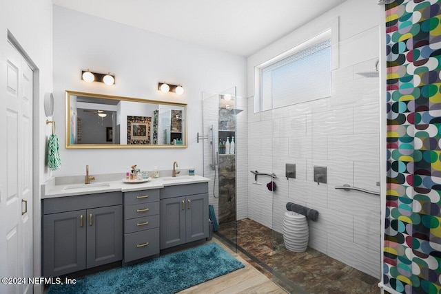 bathroom featuring double vanity, a walk in shower, a sink, and wood finished floors