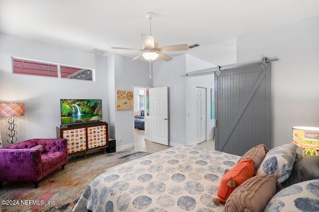 bedroom featuring baseboards, a barn door, visible vents, and a ceiling fan