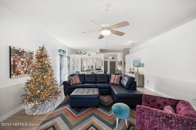 living room featuring ceiling fan, light wood finished floors, and baseboards