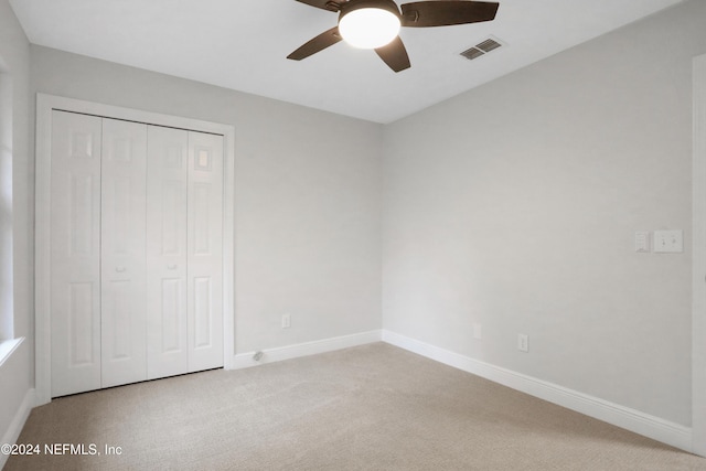 unfurnished bedroom featuring ceiling fan, light colored carpet, and a closet