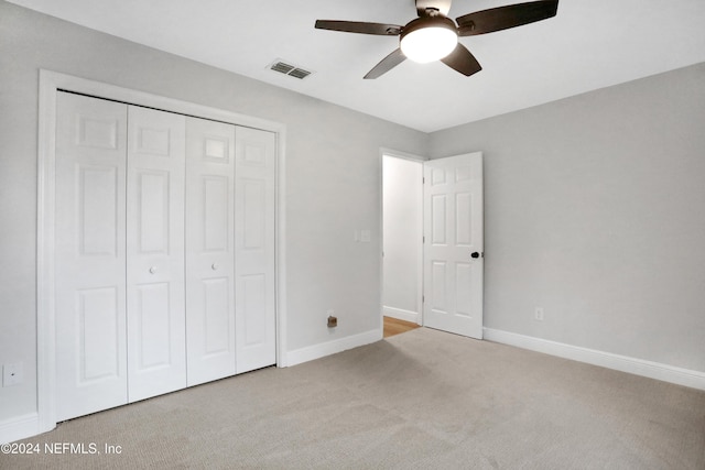 unfurnished bedroom featuring ceiling fan, a closet, and light colored carpet