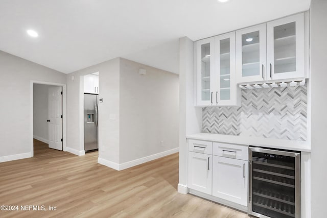 bar with backsplash, stainless steel refrigerator with ice dispenser, wine cooler, light hardwood / wood-style flooring, and white cabinetry