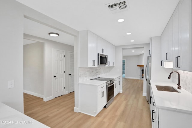 kitchen with white cabinets, sink, light wood-type flooring, and stainless steel appliances