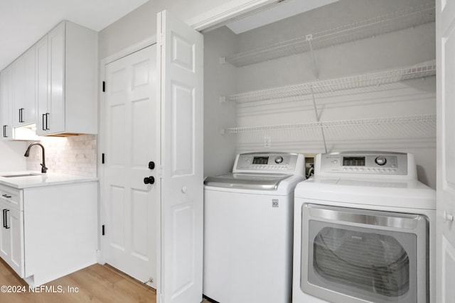 washroom featuring independent washer and dryer, sink, and light hardwood / wood-style flooring