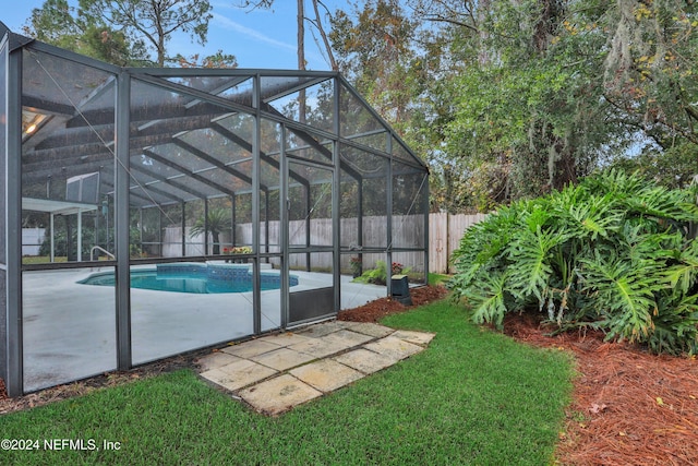 view of swimming pool with glass enclosure, a patio area, and a yard