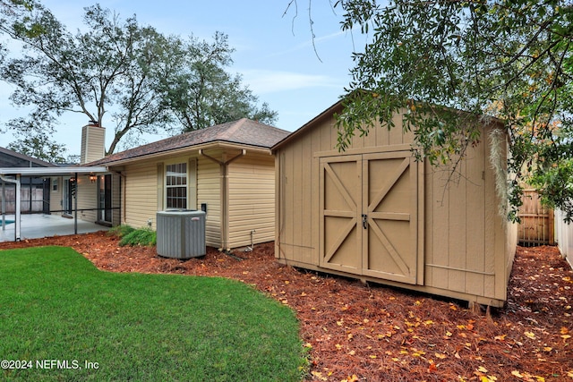 view of outbuilding with a lawn and central air condition unit