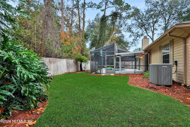 view of yard featuring a fenced in pool, glass enclosure, and central AC