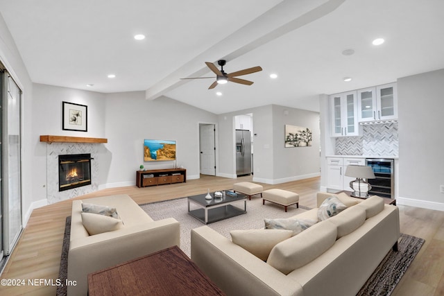 living room featuring beverage cooler, ceiling fan, light hardwood / wood-style flooring, a fireplace, and vaulted ceiling with beams