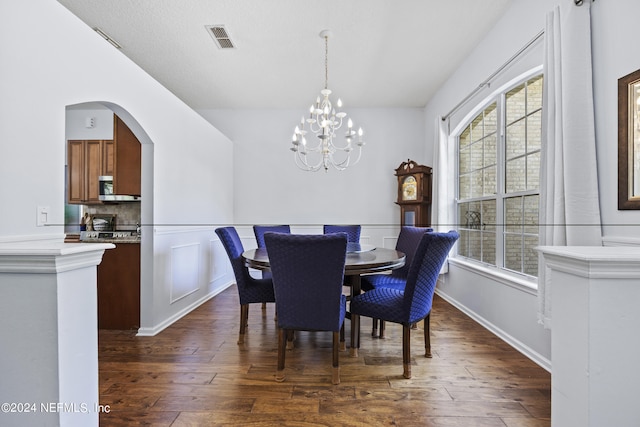 dining space with dark wood-type flooring, an inviting chandelier, and a healthy amount of sunlight