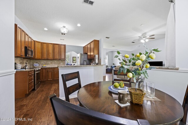 dining area featuring ceiling fan, dark wood-type flooring, and a textured ceiling