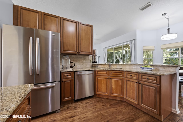 kitchen featuring kitchen peninsula, dark hardwood / wood-style flooring, stainless steel appliances, sink, and pendant lighting