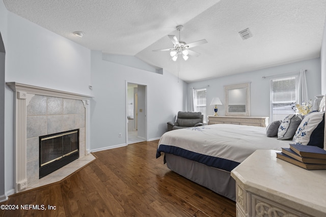 bedroom with a textured ceiling, ceiling fan, a tile fireplace, wood-type flooring, and lofted ceiling