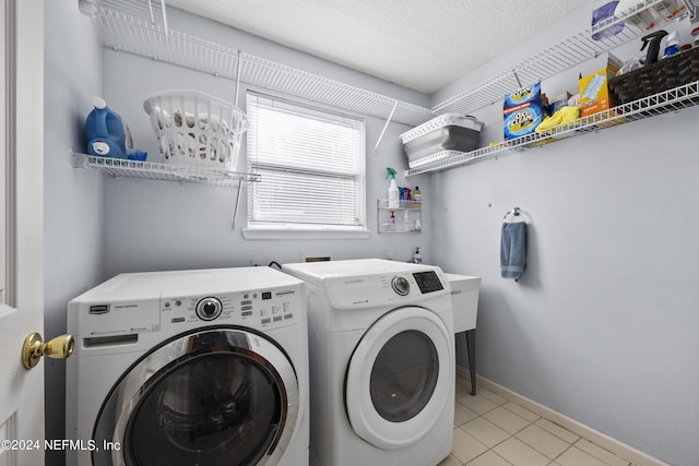 laundry room featuring light tile patterned flooring, a textured ceiling, and washing machine and clothes dryer