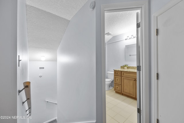 hallway with vaulted ceiling and a textured ceiling