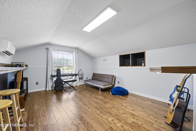 office area featuring a wall mounted air conditioner, hardwood / wood-style floors, a textured ceiling, and vaulted ceiling