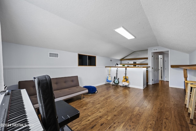 exercise room featuring a textured ceiling, lofted ceiling, and dark wood-type flooring